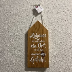 Holzsschild mit Spruch:  "Zuhause ist nicht einfach ein Ort, es ist ein wundervolles Gefühl.